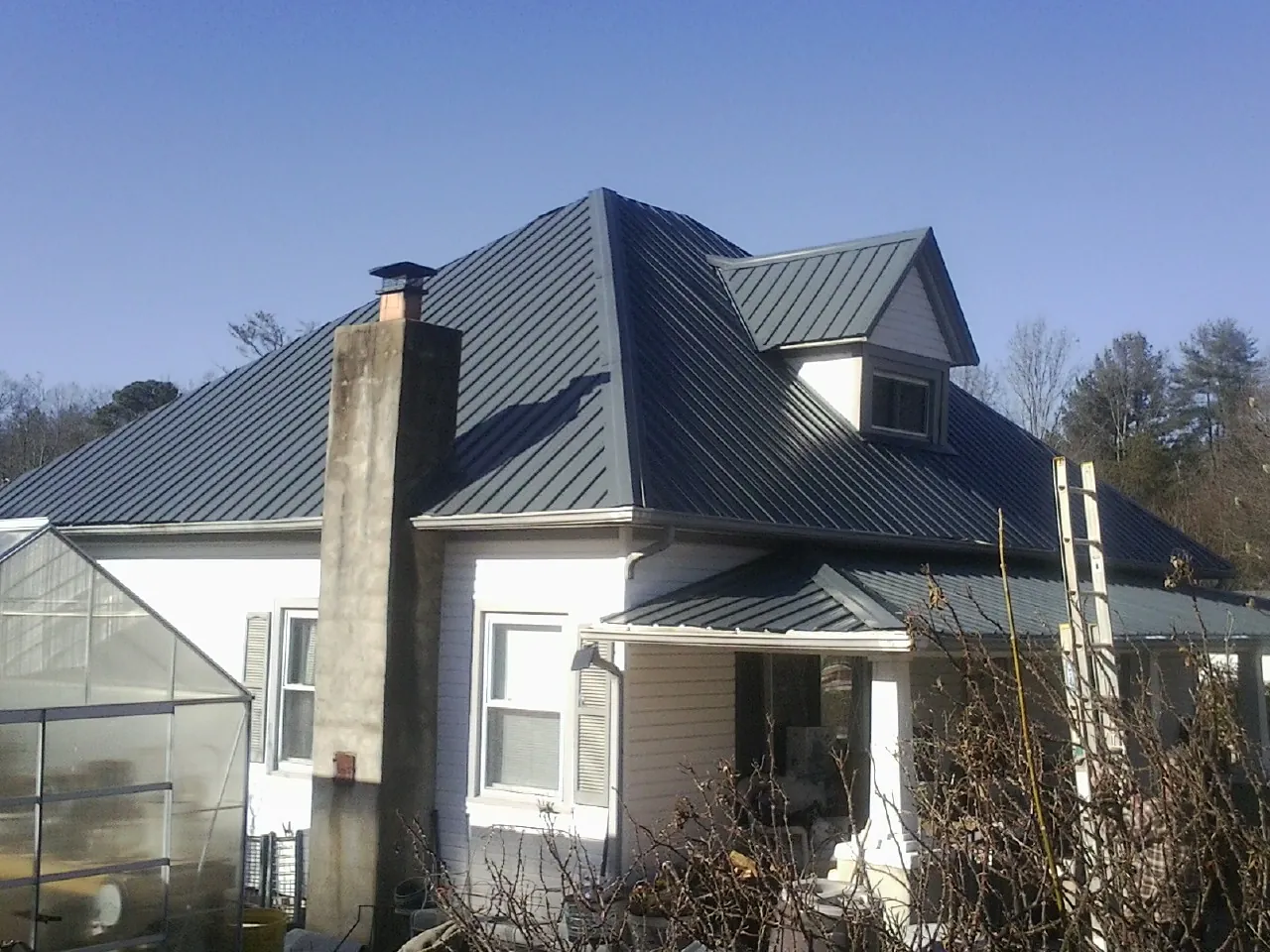 Dark blue standing seam metal roof on a white farmhouse with dormer — Slate & Tile Roof Repair by Roofing Brothers in Voluntown