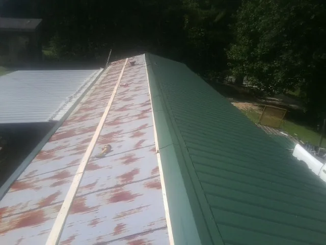 Old rusted panels beside newly installed green metal roofing — Wind Damage Roof Repair by Roofing Brothers in Voluntown