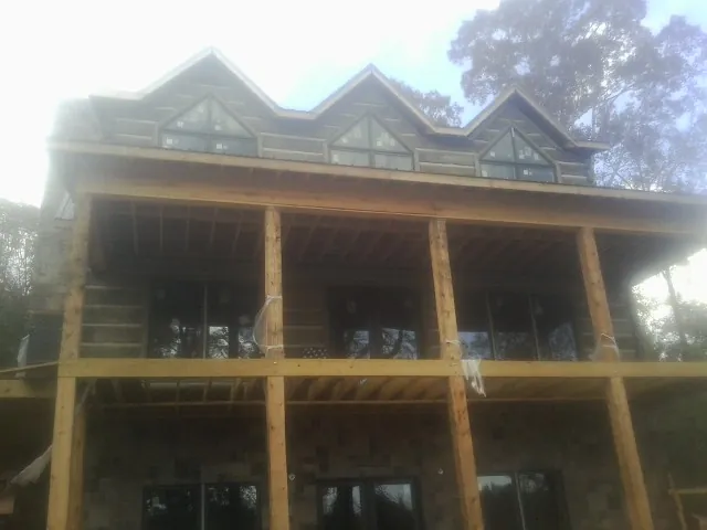 Dormers and porch framing on a large log home under construction — Roof Coating work by our crew in Voluntown