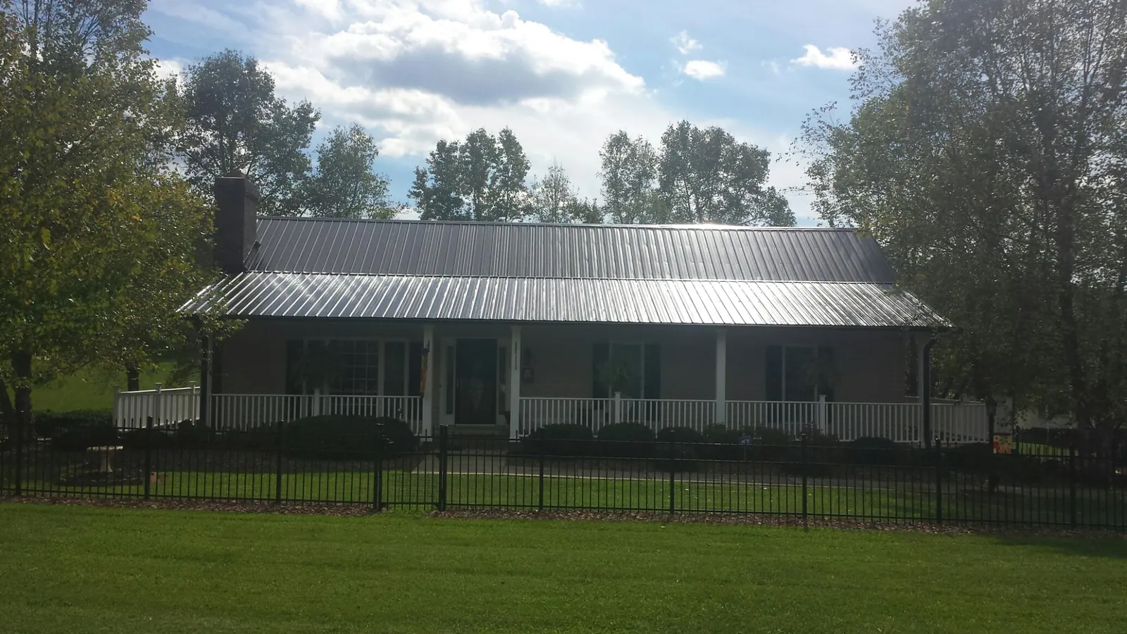 Gray metal roof on a brick ranch with a full width front porch — Gutter Guard Installation work by our crew in Voluntown
