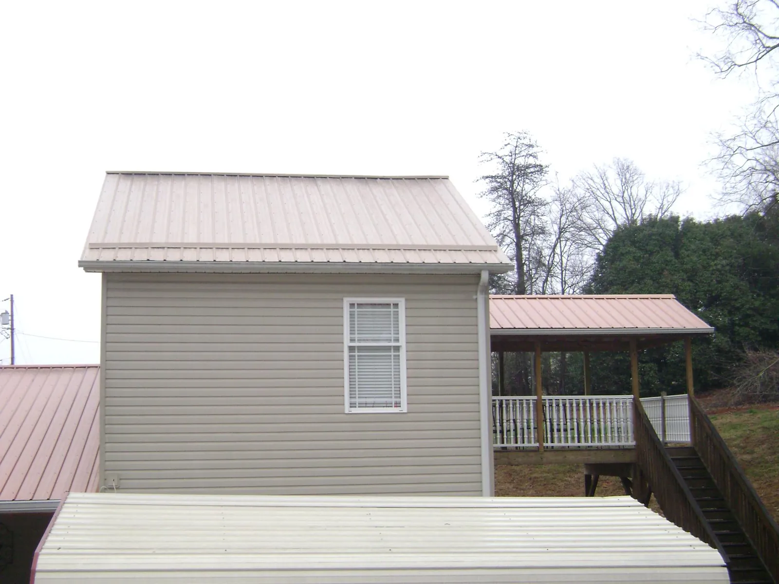 Tan metal roofs on a two story addition and attached porch, from a Roof Replacement job in Voluntown